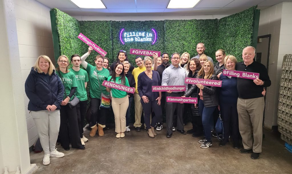 A corporate team standing in front of the Filling in the Blanks photo backdrop for a group photo