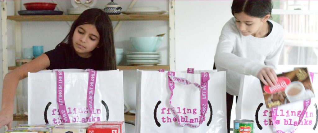 Girls adding food to a Filling in the Blanks branded bag